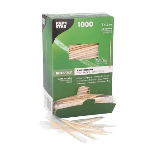 Eine grüne PAPSTAR-Schachtel mit der Aufschrift "Zahnstocher rund 6,5 cm, Holz mit Mentholgeschmack" (1000 Stück) zeigt Zahnstocher aus Holz durch ein Fenster. Davor liegen einige einzeln verpackte Zahnstocher für eine bessere Mundhygiene aus.