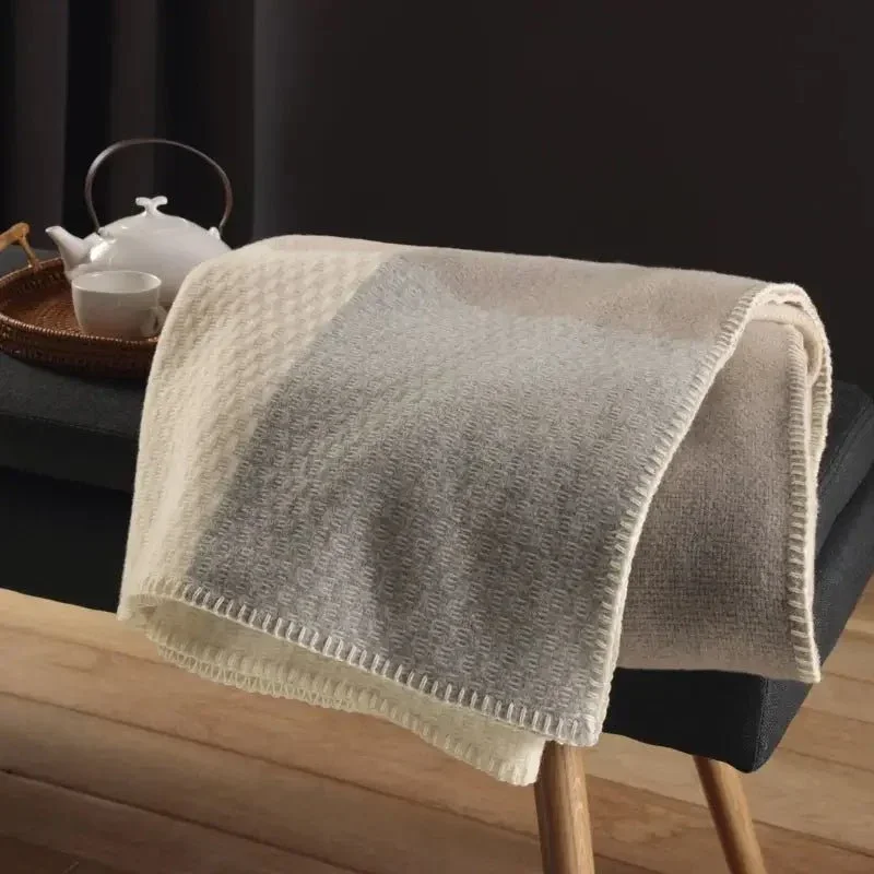 Merinowolle Kuscheldecke in Naturtönen auf einer Bank im Wohnzimmer, weich und strukturiert gewebt