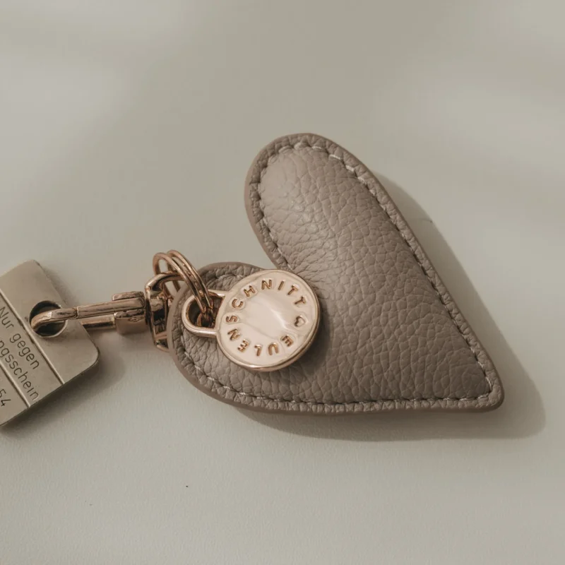 Schlüsselanhänger Herz aus grauem Leder mit rundem Metallplättchen und Karabiner